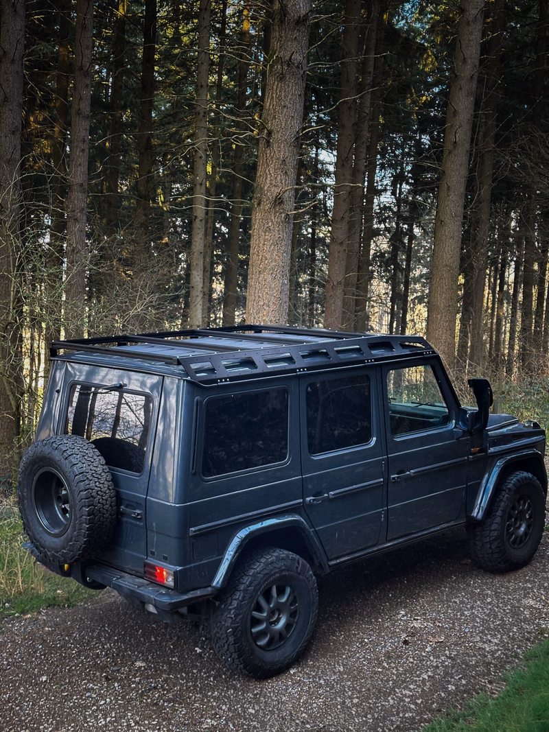 Dunkle G-Klasse Heckansicht mit Walger Works Dachtraeger im Wald